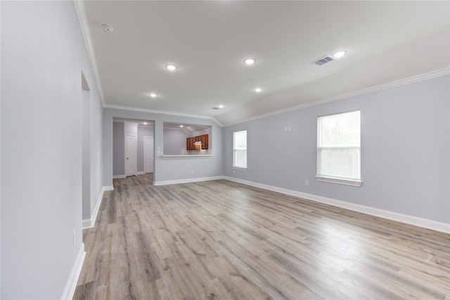 unfurnished living room with light wood-type flooring, vaulted ceiling, and crown molding