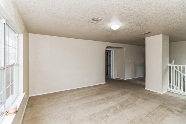 carpeted empty room with a textured ceiling