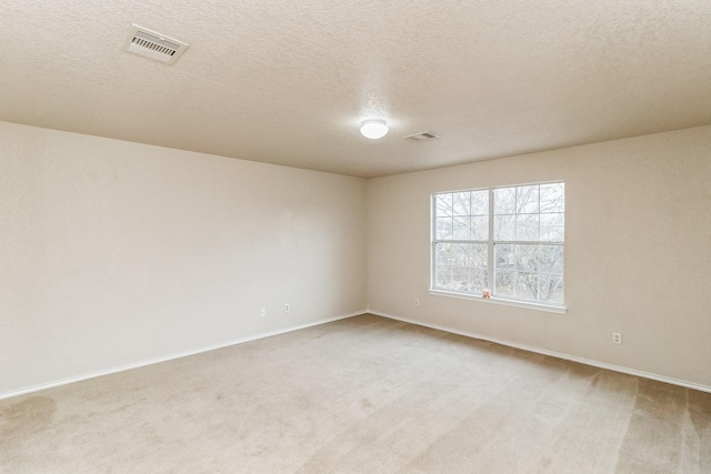 unfurnished room featuring a textured ceiling and light colored carpet