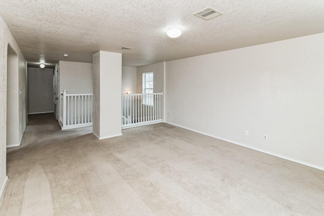 carpeted spare room with a textured ceiling