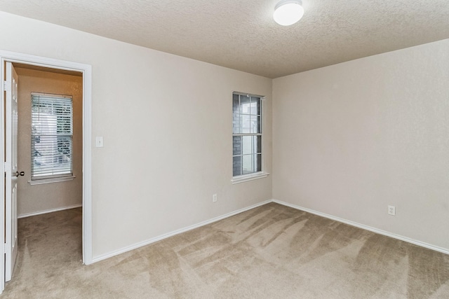 empty room with light carpet and a textured ceiling