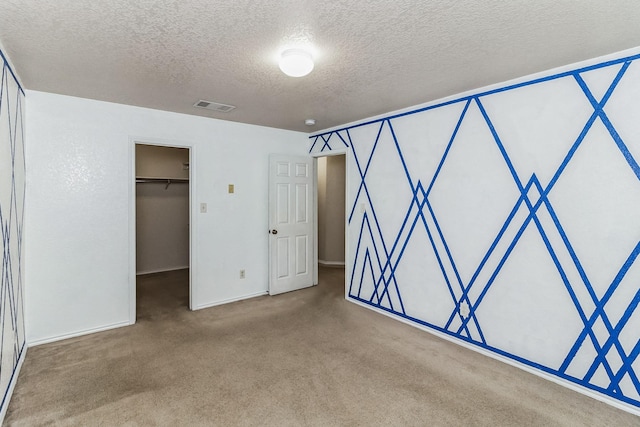 unfurnished bedroom featuring a textured ceiling, light carpet, a walk in closet, and a closet