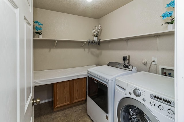 washroom featuring a textured ceiling, separate washer and dryer, and dark tile patterned flooring