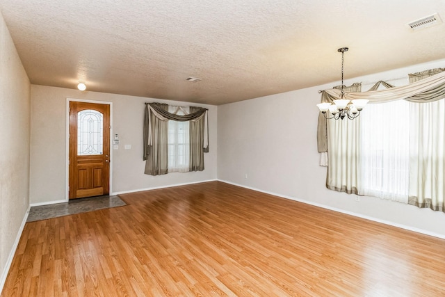 foyer featuring a textured ceiling, hardwood / wood-style flooring, and a chandelier