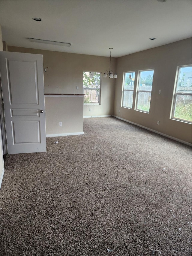 carpeted spare room featuring a chandelier