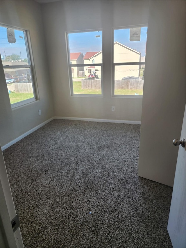 spare room with dark colored carpet and a healthy amount of sunlight