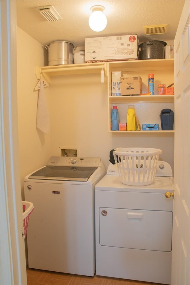 clothes washing area with independent washer and dryer and a textured ceiling