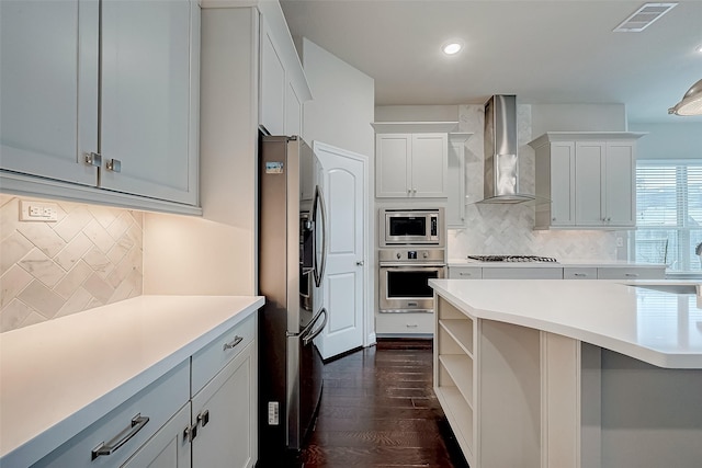 kitchen featuring white cabinets, stainless steel appliances, dark hardwood / wood-style floors, and wall chimney range hood