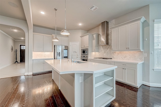 kitchen featuring a kitchen island with sink, wall chimney exhaust hood, appliances with stainless steel finishes, dark hardwood / wood-style flooring, and white cabinetry