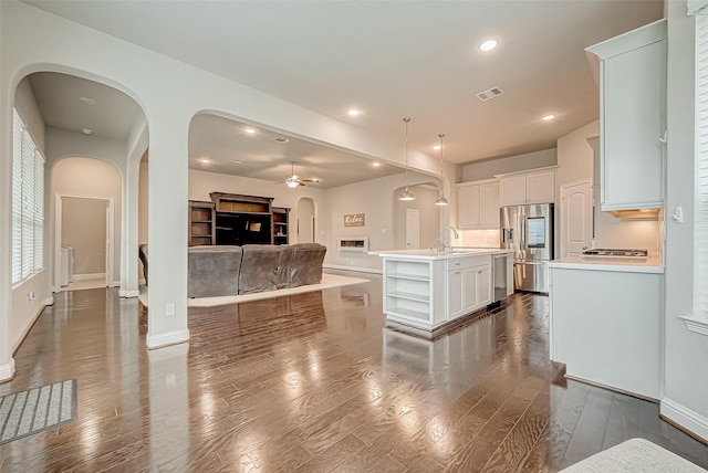 kitchen featuring decorative light fixtures, wood-type flooring, a kitchen island with sink, and stainless steel appliances