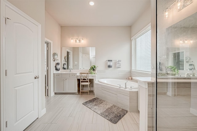 bathroom featuring tiled bath and vanity