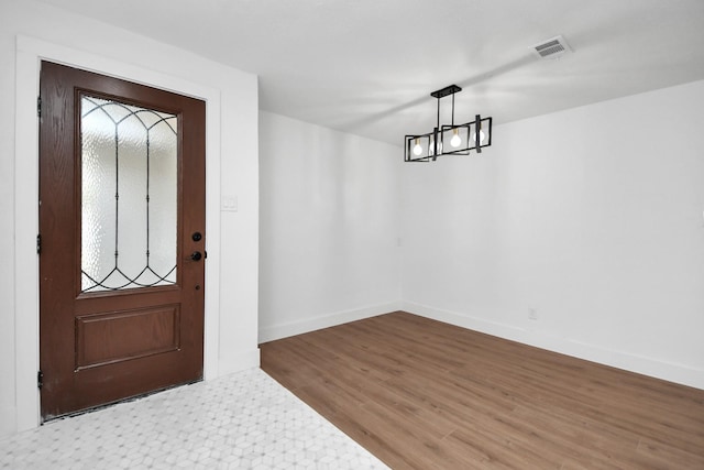 foyer entrance with hardwood / wood-style floors and a chandelier