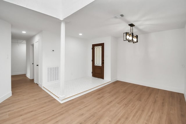 empty room with an inviting chandelier and light hardwood / wood-style flooring