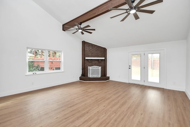 unfurnished living room with beamed ceiling, a healthy amount of sunlight, a brick fireplace, and light hardwood / wood-style flooring