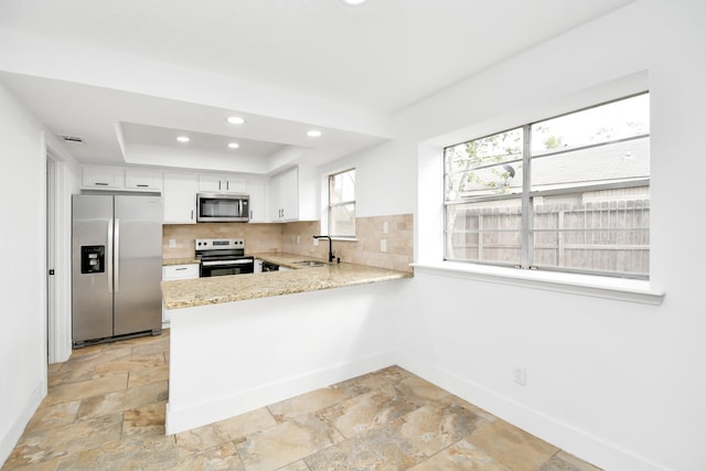 kitchen with white cabinetry, a raised ceiling, backsplash, kitchen peninsula, and appliances with stainless steel finishes