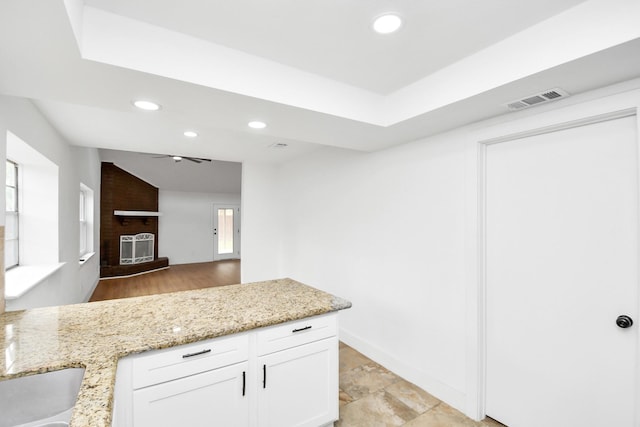 kitchen with white cabinetry, sink, light stone countertops, and a fireplace