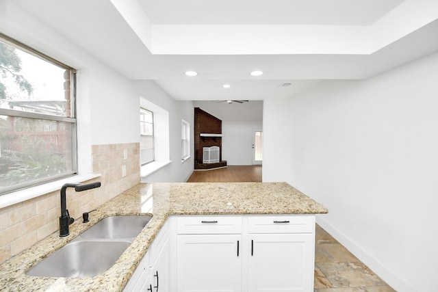 kitchen featuring decorative backsplash, light stone counters, white cabinetry, and sink