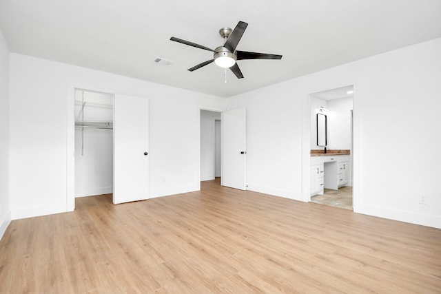 unfurnished bedroom featuring connected bathroom, light hardwood / wood-style flooring, and a closet