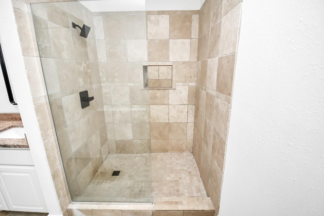 bathroom featuring a tile shower and vanity