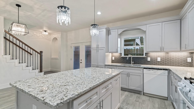 kitchen featuring a center island, sink, french doors, white dishwasher, and pendant lighting