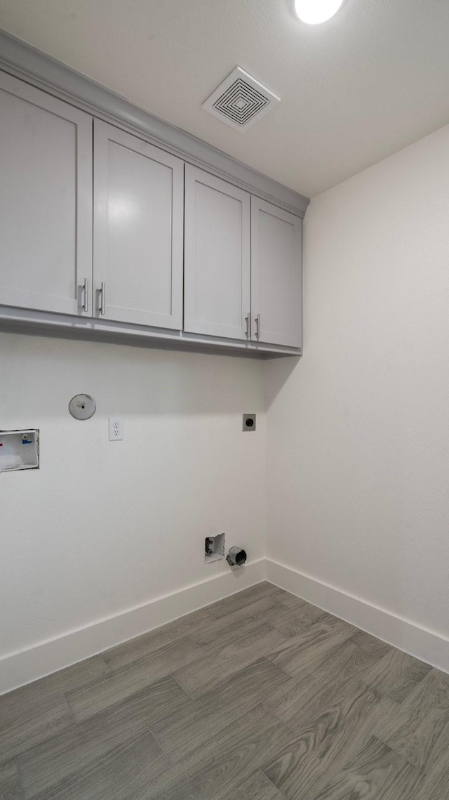 washroom with cabinets, hookup for a washing machine, gas dryer hookup, dark wood-type flooring, and electric dryer hookup