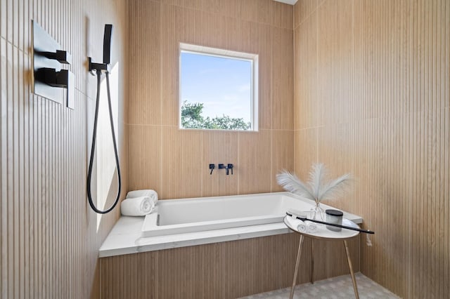 bathroom with tile patterned flooring and a relaxing tiled tub