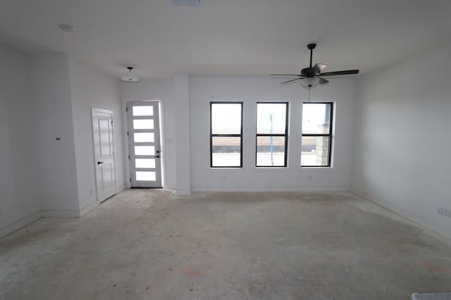 empty room featuring concrete flooring, a healthy amount of sunlight, visible vents, and baseboards