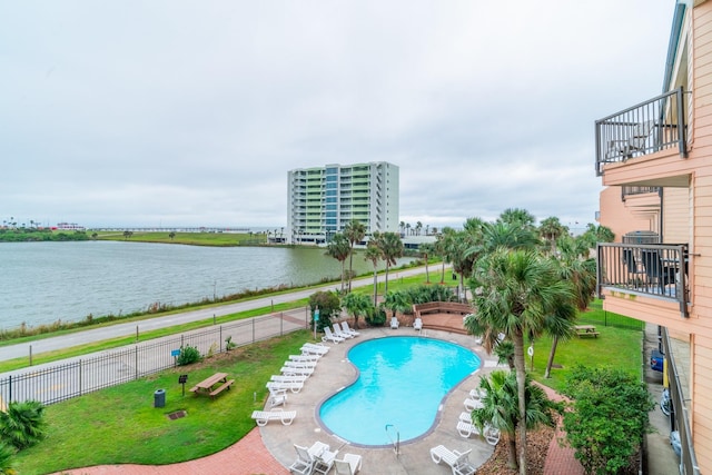 view of pool with a patio area, a water view, and a yard