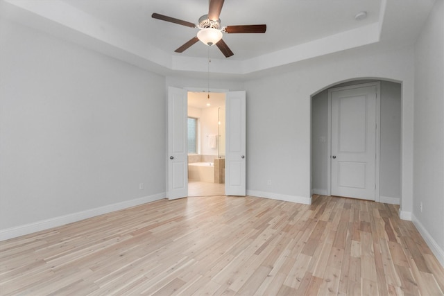 interior space with a raised ceiling, light hardwood / wood-style flooring, and ceiling fan