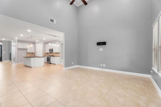 unfurnished living room featuring ceiling fan, light tile patterned floors, and sink