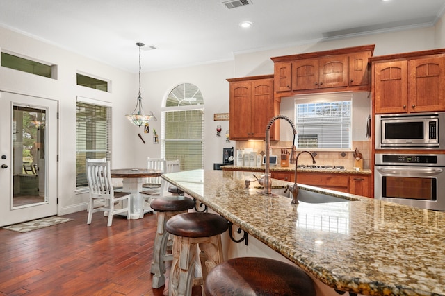 kitchen featuring hanging light fixtures, decorative backsplash, light stone countertops, dark hardwood / wood-style flooring, and stainless steel appliances