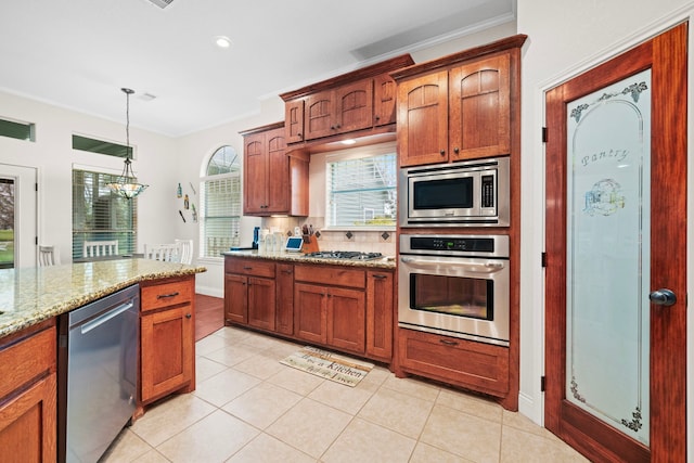 kitchen with hanging light fixtures, stainless steel appliances, tasteful backsplash, light stone counters, and light tile patterned floors