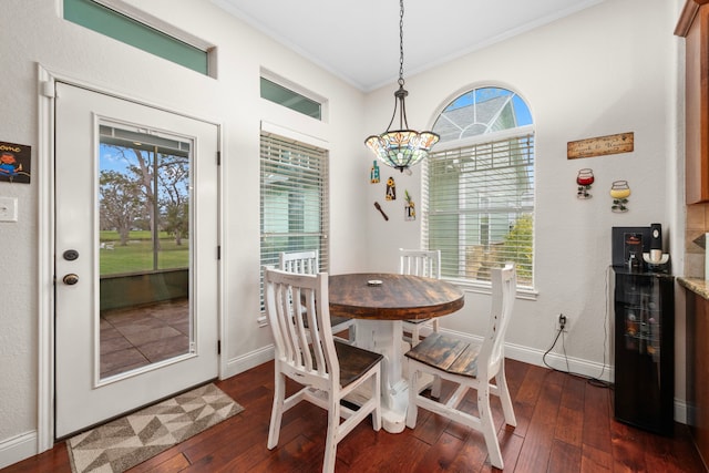 dining area featuring dark wood-type flooring, a notable chandelier, and ornamental molding