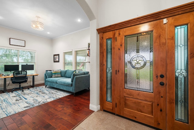 foyer with light wood-type flooring and crown molding