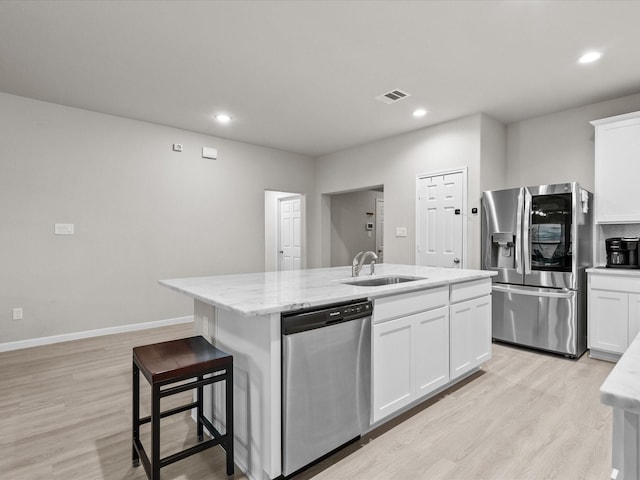 kitchen with a center island with sink, white cabinets, sink, and appliances with stainless steel finishes