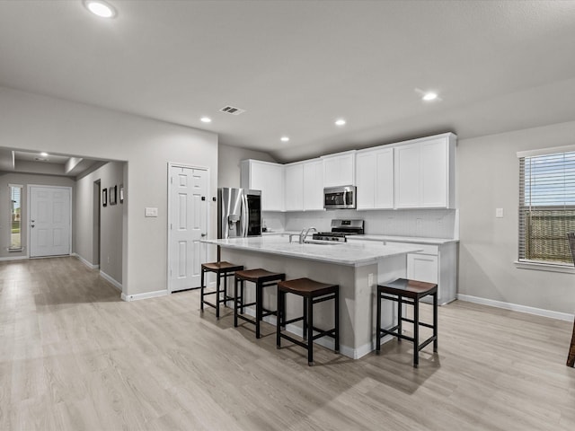 kitchen with white cabinets, appliances with stainless steel finishes, and an island with sink