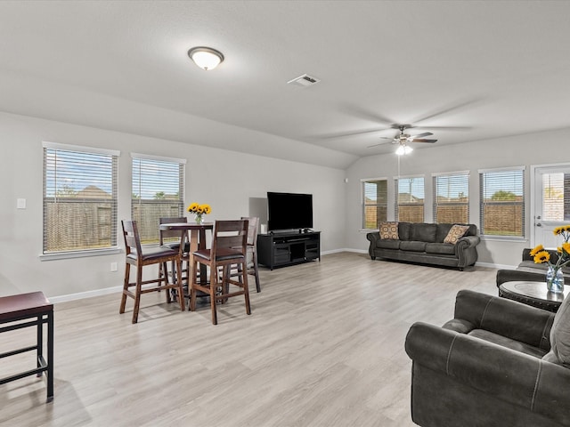 living room with ceiling fan, a healthy amount of sunlight, light wood-type flooring, and vaulted ceiling