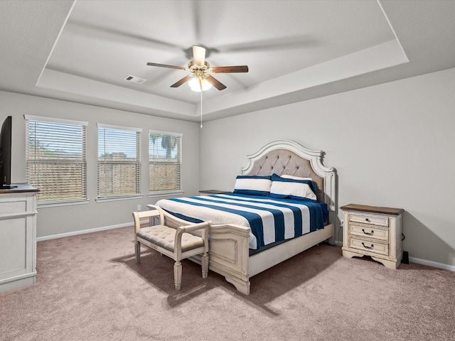 carpeted bedroom with ceiling fan and a tray ceiling