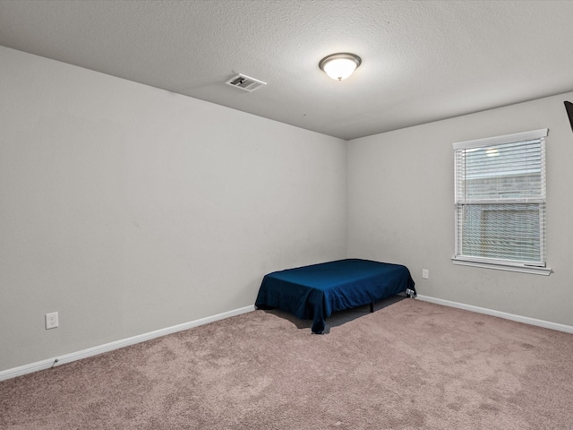 unfurnished bedroom featuring a textured ceiling and light colored carpet