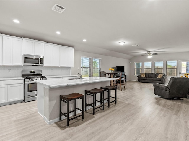 kitchen with a center island with sink, white cabinets, sink, a breakfast bar area, and stainless steel appliances