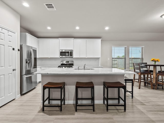 kitchen featuring white cabinets, stainless steel appliances, a kitchen island with sink, and sink