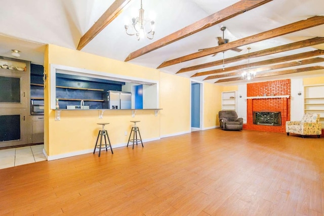 unfurnished living room featuring a fireplace, light wood-type flooring, lofted ceiling with beams, and an inviting chandelier