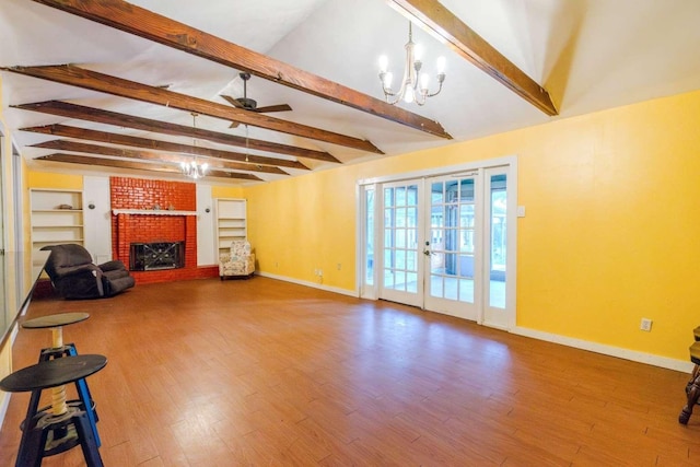 living room featuring french doors, ceiling fan with notable chandelier, hardwood / wood-style flooring, and a brick fireplace