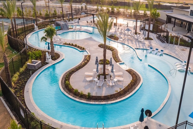 community pool featuring fence and a hot tub