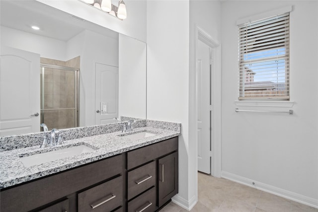 bathroom featuring a stall shower, a sink, baseboards, and double vanity