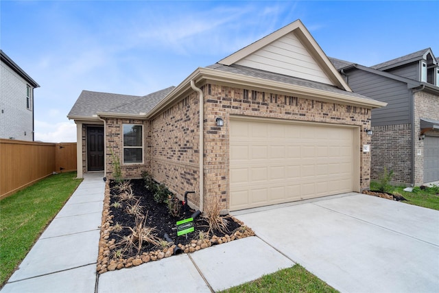 view of front of home featuring brick siding, roof with shingles, concrete driveway, fence, and a garage