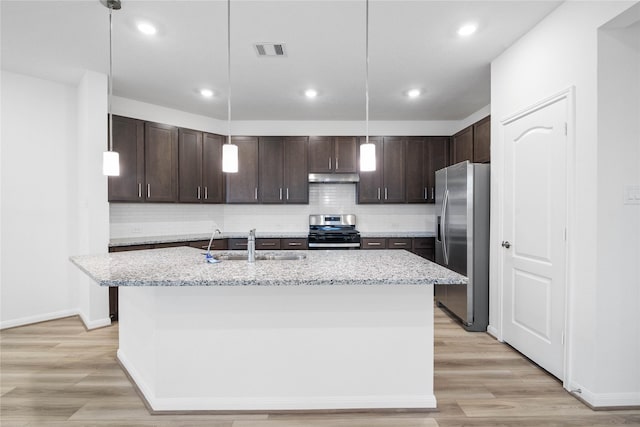 kitchen with under cabinet range hood, stainless steel appliances, a sink, light wood-style floors, and dark brown cabinets