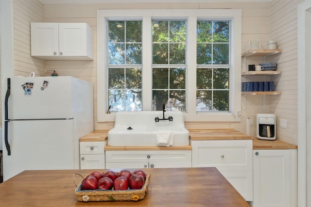 kitchen with white cabinets, wooden counters, and white fridge