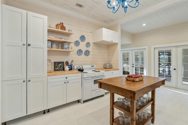 kitchen featuring french doors, wooden walls, white stove, butcher block countertops, and white cabinetry