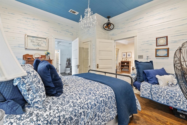 bedroom featuring wood walls, dark hardwood / wood-style floors, and an inviting chandelier